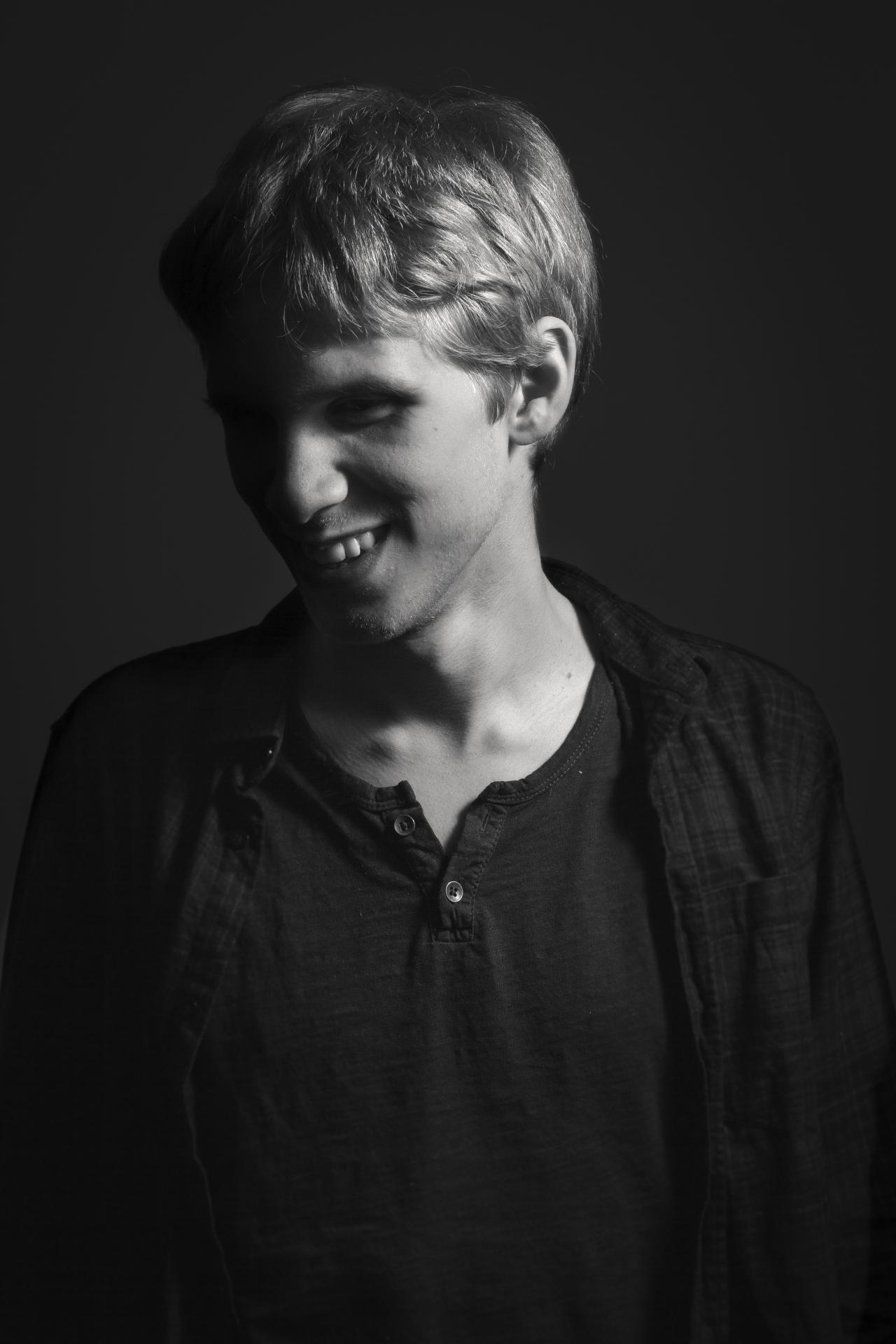 Mustavalkoinen kuva, jossa Tuukka katsoo hymyillen vasemmalle alas. 