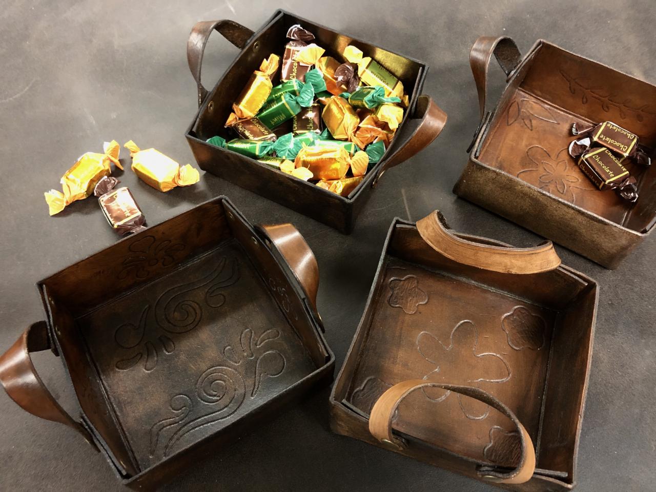 Neliönmuotoisia nahkarasioita, joiden sisäpohjaan on kaiverrettu kuviointeja.