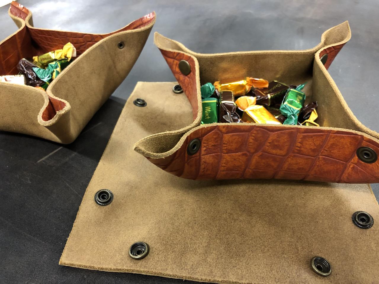 Neliön mallisesta nahkapalasta kulmaneppareilla koottuja nahkarasioita.