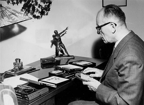 Sokeain Keskusliiton ensimmäinen puheenjohtaja Einar Juvonen. Hän istuu kirjoituspöydän ääressä ja pöydällä on useampia äänikirjoja. Juvonen pitää kädessään yhtä ääninauhaa.