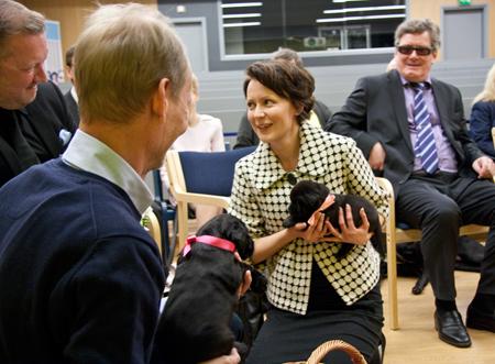 Jenni Haukio opaskoiranpentu sylissään.