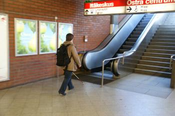 Nainen on astumassa ylöspäin meneviin liukuportaisiin Itäkeskuksen metroasemalla.