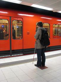 Nainen seisoo metrolaiturilla. Hänen edessään on metrojuna, jolla on ovet kiinni.