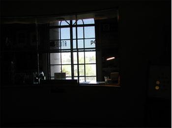 Taustalla on ikkuna, josta tulee valoa sisään tummaan huoneeseen.