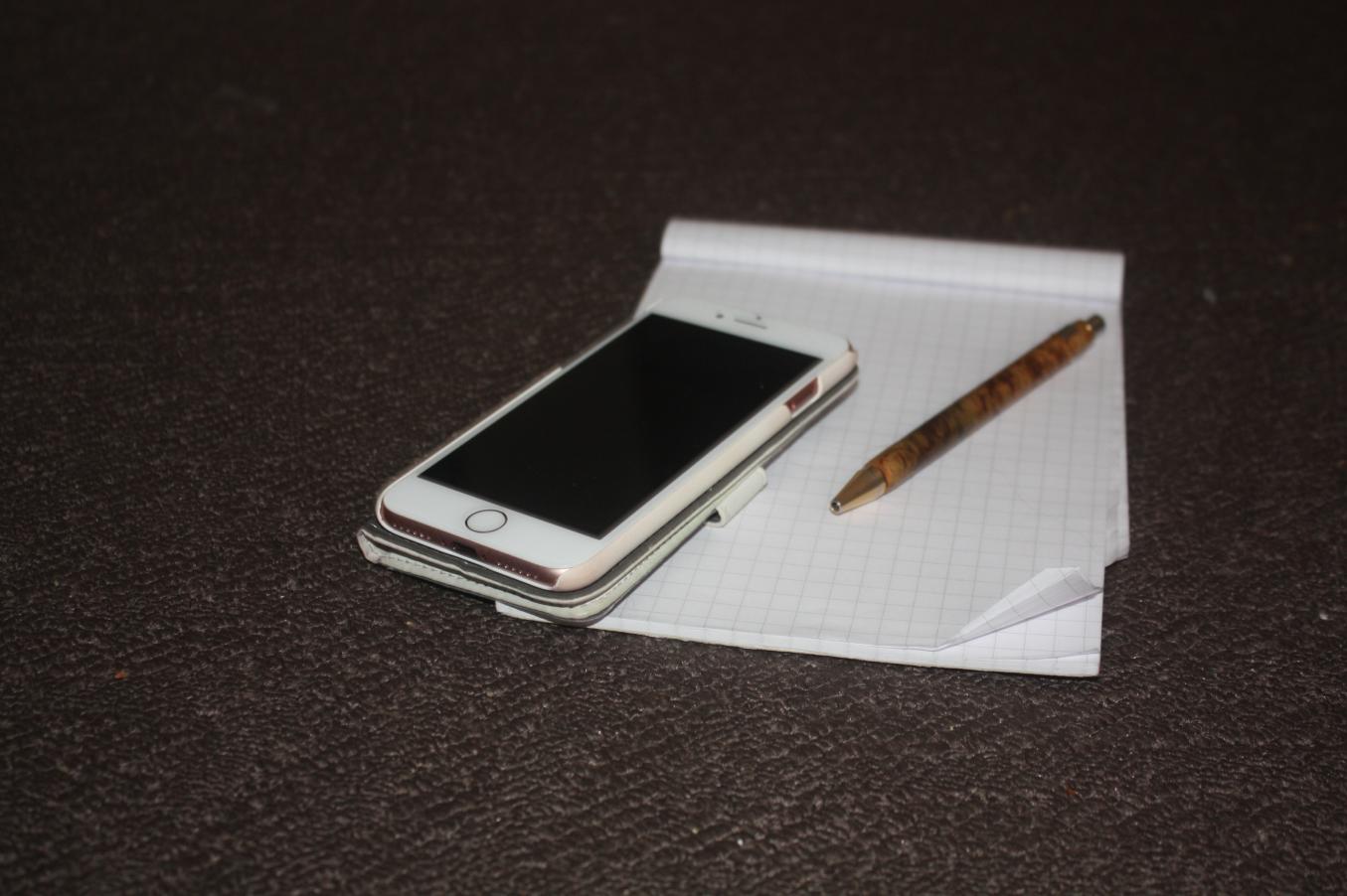 Yhteydenottovcälineitä: Kännykkä, kynä ja lehtiö.