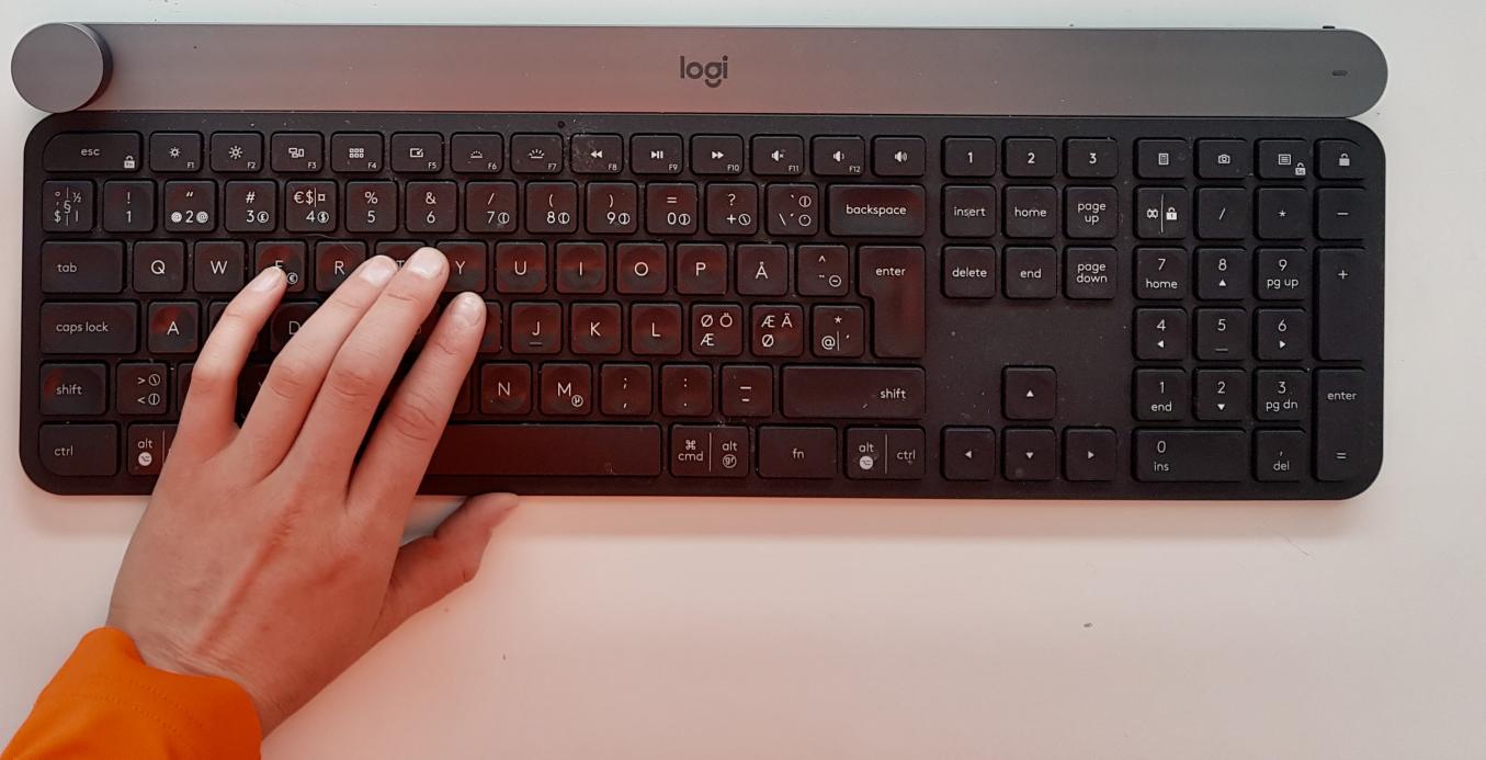 Musta näppäimistö, jossa naisen vasen käsi näppäimistön päällä.