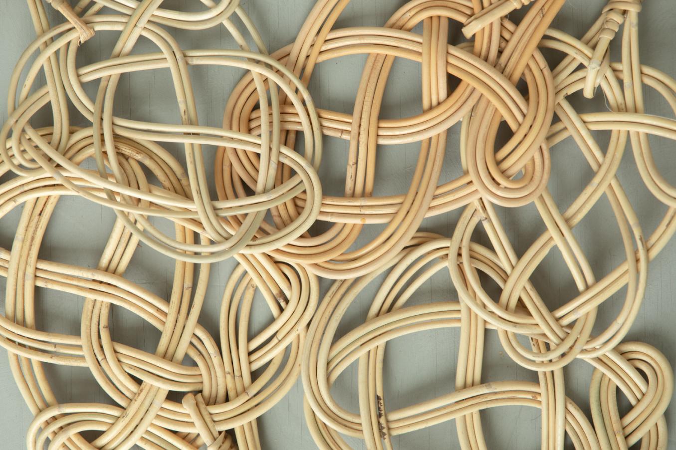 Useita rottingista tehtyjä mattopiiskoja sikin sokin harmaalla taustalla.