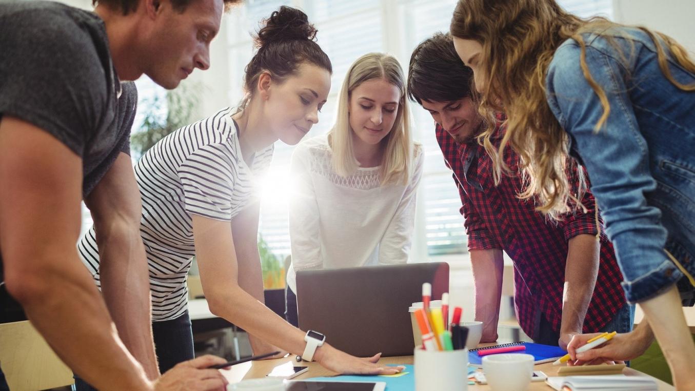 Ryhmä ihmisiä pöydän ympärillä.