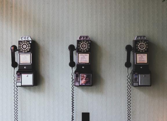 Kolme vanhaa seinäpuhelinta.