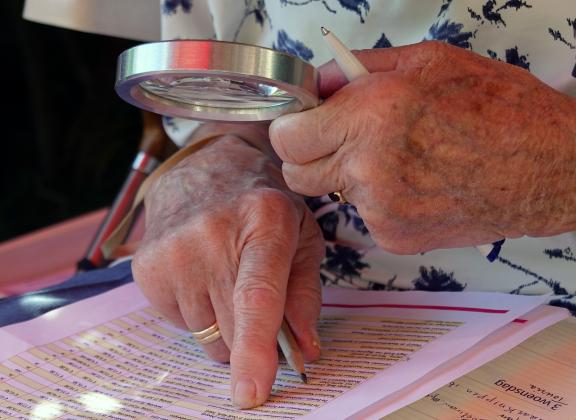 Suurennuslasia käyttävä henkilö.